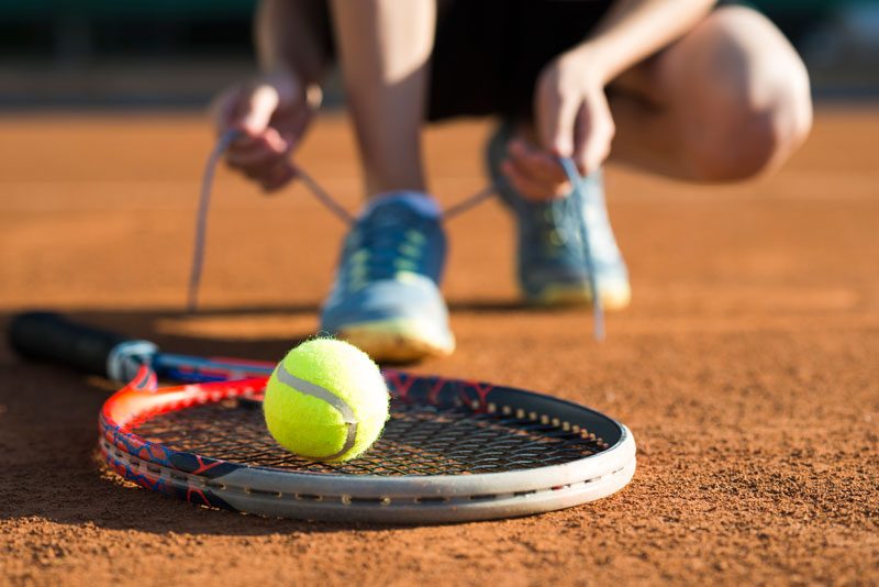 Joueuse de tennis laçant ses chaussures sur terre battue